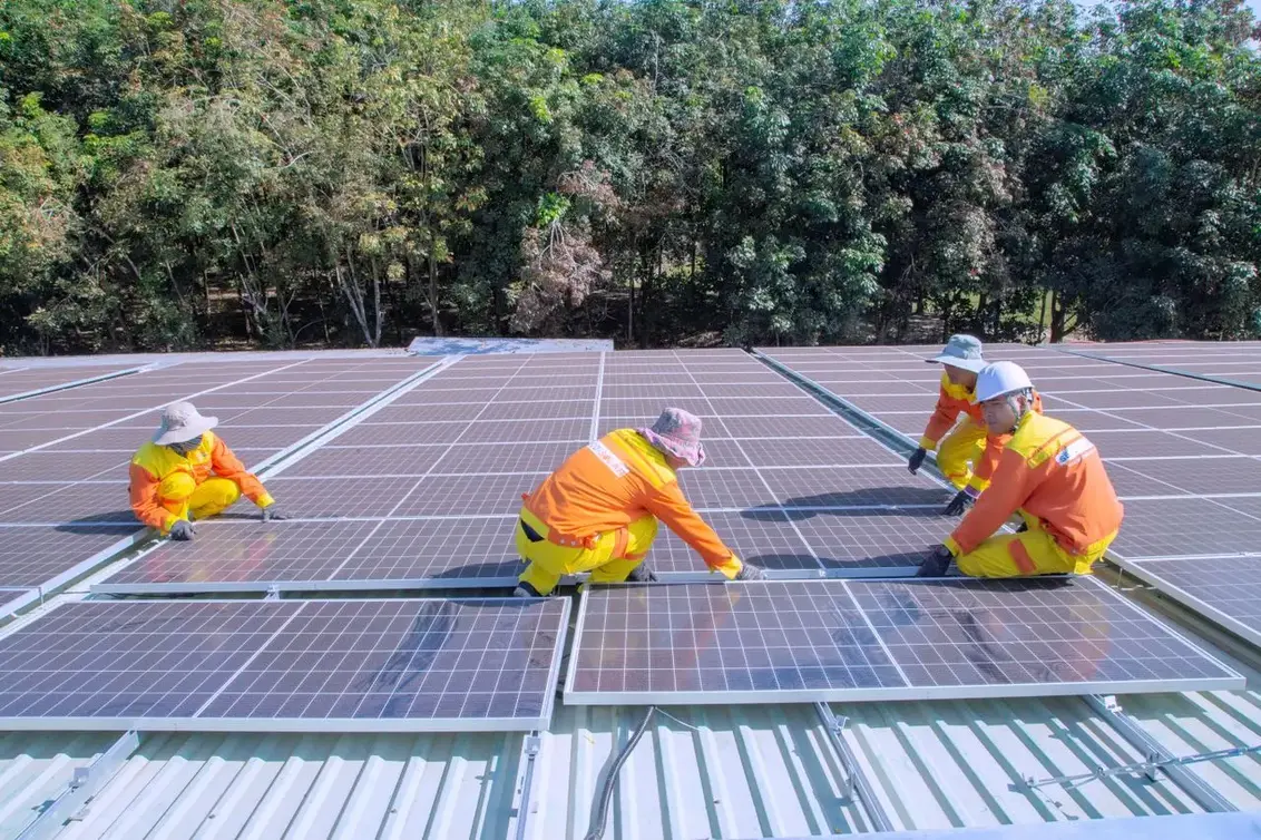 Two installers fitting solar panels on a residential roof in bright sunshine